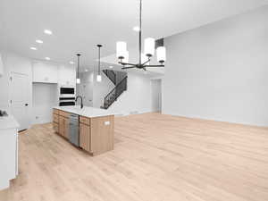 Kitchen featuring stainless steel appliances, light wood-style flooring, open floor plan, recessed lighting, and light countertops