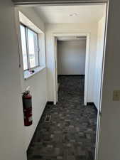 Hallway featuring visible vents, dark carpet, a textured ceiling, and baseboards
