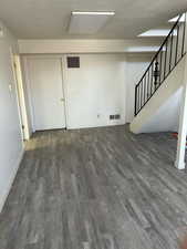 Basement featuring stairs, a textured ceiling, wood finished floors, and visible vents