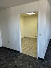 Unfurnished room featuring dark carpet, dark wood finished floors, visible vents, and baseboards