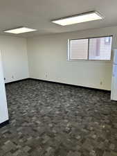 Empty room featuring a textured ceiling, carpet flooring, and baseboards