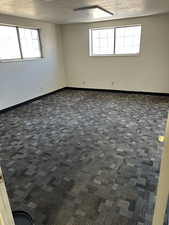 Empty room featuring a textured ceiling, baseboards, and carpet flooring