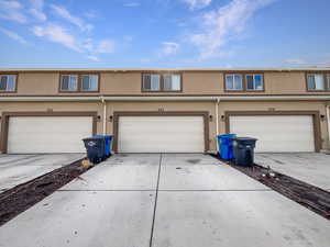 Townhome / multi-family property with a garage, concrete driveway, and stucco siding