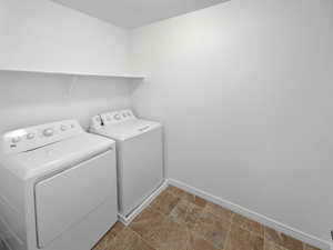 Clothes washing area with laundry area, independent washer and dryer, and baseboards