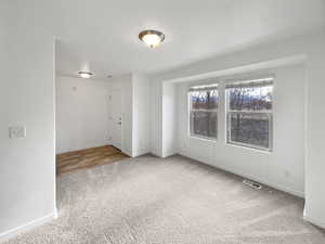 Carpeted spare room featuring baseboards and visible vents