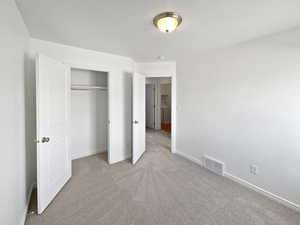 Unfurnished bedroom with baseboards, a closet, visible vents, and carpet flooring