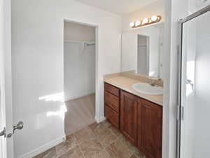 Full bath featuring stone finish floor, an enclosed shower, vanity, and baseboards