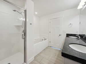 Full bathroom featuring a garden tub, a sink, and a shower stall