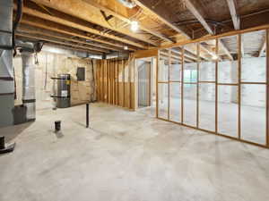 Basement featuring strapped water heater, electric panel, and heating unit