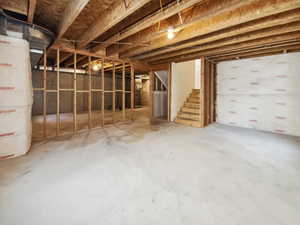 Unfinished below grade area featuring stairs and water heater