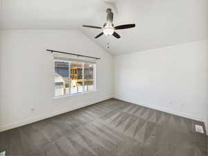 Unfurnished room featuring carpet floors, a ceiling fan, visible vents, vaulted ceiling, and baseboards