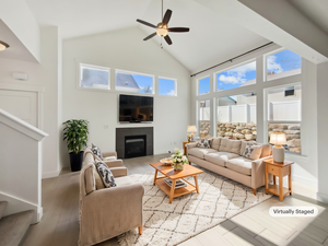 Living room with a fireplace, ceiling fan, wood finished floors, high vaulted ceiling, and baseboards