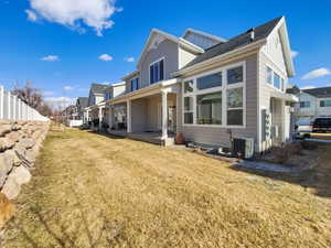 View of side of property with central AC, fence, a lawn, a residential view, and board and batten siding