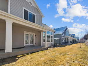 Back of house with french doors, central air condition unit, a lawn, a patio area, and a residential view