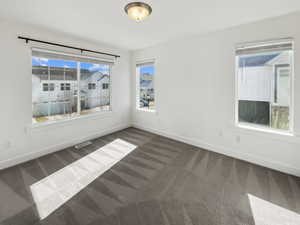 Carpeted empty room featuring visible vents and baseboards