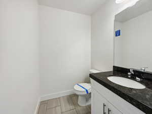 Half bathroom featuring vanity, toilet, and baseboards