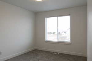 Unfurnished room with dark carpet, visible vents, and baseboards