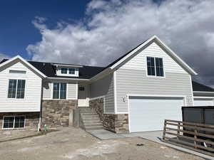 View of front facade featuring a garage, stone siding, and concrete driveway