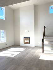 Unfurnished living room with stairs, wood finished floors, a towering ceiling, and baseboards