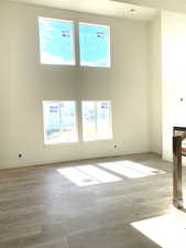 Unfurnished living room with a towering ceiling, baseboards, and wood finished floors