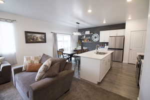 Kitchen with stainless steel appliances, light countertops, open floor plan, white cabinets, and a sink