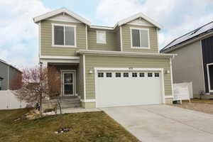 View of front of home with an attached garage, fence, a front lawn, and concrete driveway