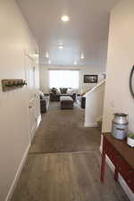 Hall featuring recessed lighting, carpet flooring, wood finished floors, baseboards, and stairway