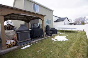 Rear view of house featuring a trampoline, a fenced backyard, a yard, and stucco siding