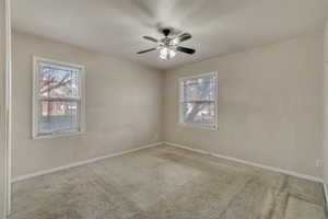 Unfurnished room with light colored carpet, plenty of natural light, and ceiling fan