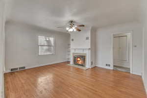 Unfurnished living room with light wood-type flooring, a fireplace, and visible vents