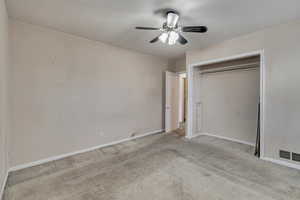 Unfurnished bedroom featuring ceiling fan, light colored carpet, visible vents, baseboards, and a closet