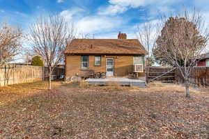 Rear view of house featuring a fenced backyard, brick siding, a chimney, and a wooden deck