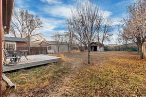 View of yard featuring an outdoor structure, a wooden deck, and a storage shed