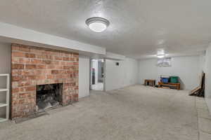 Finished below grade area with carpet floors, a fireplace, and a textured ceiling