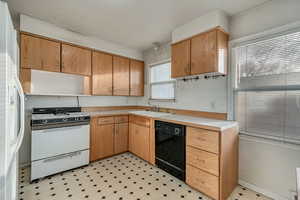 Kitchen with white appliances, tasteful backsplash, light countertops, light floors, and a sink