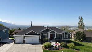 View of front of property featuring a shingled roof, an attached garage, a front lawn, a mountain view, and driveway