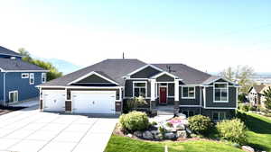 View of front of home featuring an attached garage, a front lawn, stone siding, a mountain view, and driveway