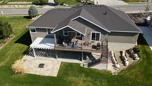 Back of property with a lawn, a deck, a patio, stairs, and stucco siding