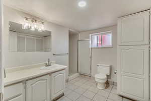 Full bathroom featuring tile patterned flooring, a shower stall, toilet, and vanity