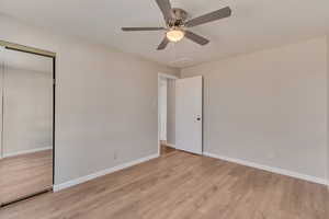 Unfurnished bedroom with a closet, baseboards, ceiling fan, and light wood finished floors