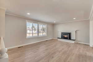 Unfurnished living room with fireplace, light wood-type flooring, and crown molding