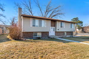 Split foyer home with a front yard, a chimney, and entry steps