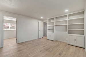 Interior space featuring ornamental molding, light wood-style floors, recessed lighting, and baseboards