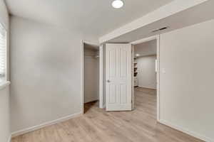 Unfurnished bedroom with a closet, visible vents, light wood-style flooring, and baseboards