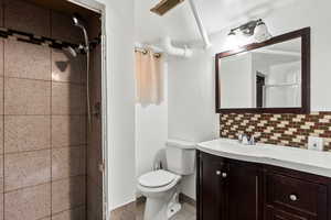 Full bathroom featuring vanity, a shower stall, tasteful backsplash, and speckled floor