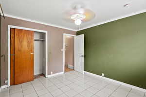 Unfurnished bedroom with a closet, crown molding, and a ceiling fan