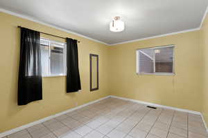 Spare room with crown molding and light tile patterned flooring