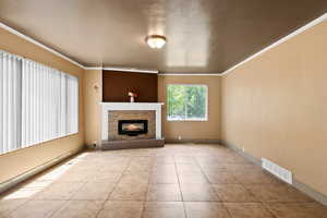 Unfurnished living room featuring ornamental molding, a glass covered fireplace, and tile patterned floors