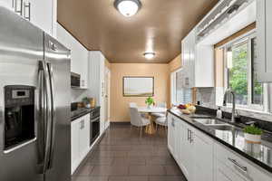 Kitchen with appliances with stainless steel finishes, decorative backsplash, and white cabinets