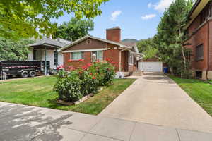 View of front facade featuring a chimney, brick siding, a front lawn, an outbuilding, and entry steps